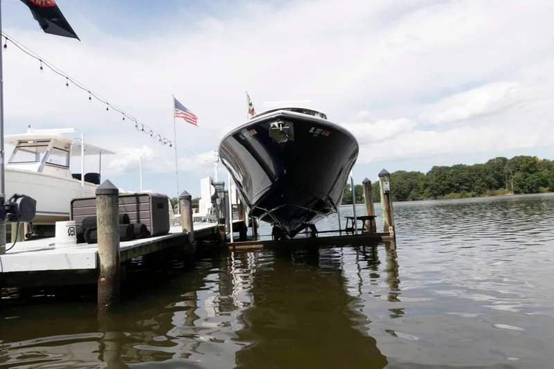 Slide: The Image of 2020 Cobia 320 Center Console boat docked on a lift by the water. - 5