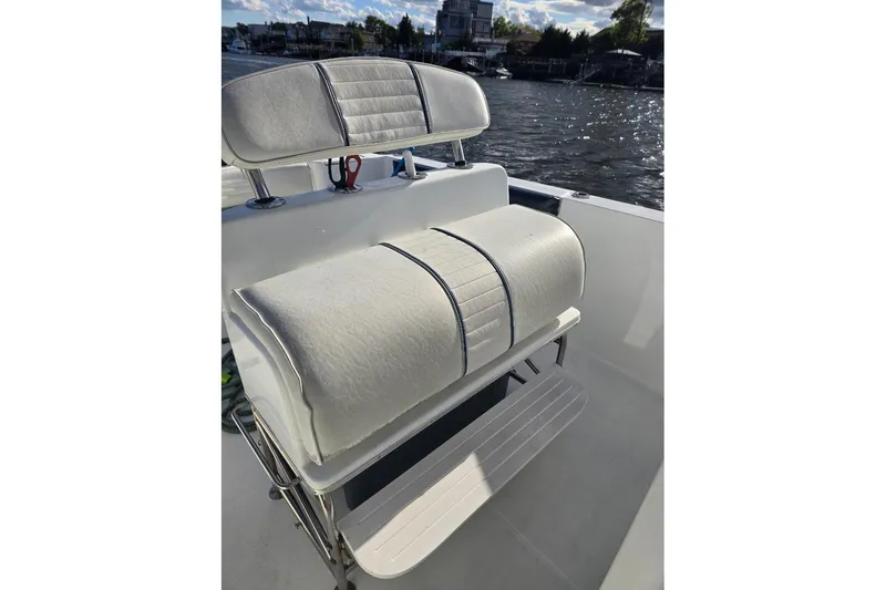 Slide: The Image of 2004 Polar 23 CC boat with white cushioned seating, docked by a scenic waterfront. - 10