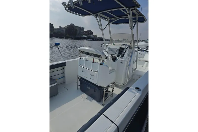 Slide: The Image of 2004 Polar 23 CC boat interior with steering console and seating, docked by a waterfront. - 4