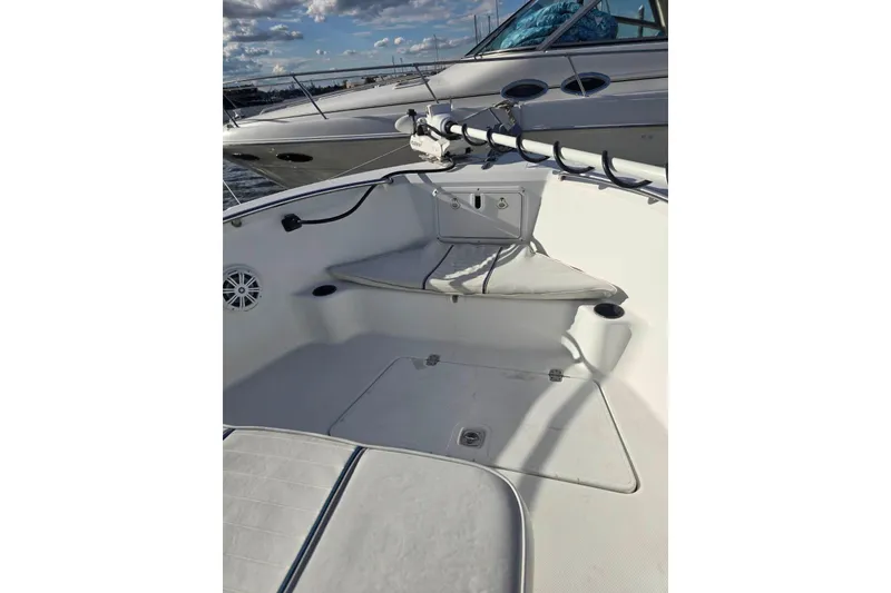 Slide: The Image of 2004 Polar 23 CC boat interior with seating and storage, docked under a cloudy sky. - 9