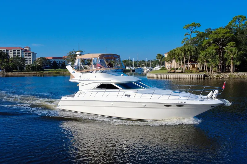 Slide: The Image of 2003 Sea Ray 400 Sedan Bridge cruising on a scenic waterway with lush greenery. - 10