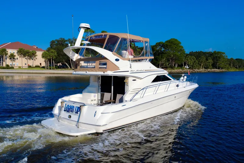 Slide: The Image of 2003 Sea Ray 400 Sedan Bridge cruising on a scenic waterway under clear blue skies. - 12