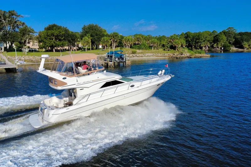 Slide: The Image of 2003 Sea Ray 400 Sedan Bridge cruising on a scenic river under a clear blue sky. - 13