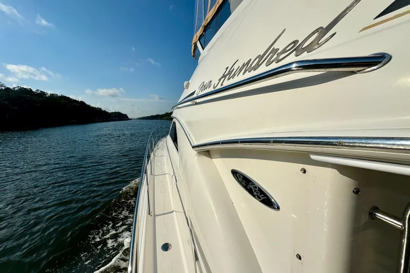 Slide: The Image of 2003 Sea Ray 400 Sedan Bridge cruising on a scenic waterway under a clear blue sky. - 16