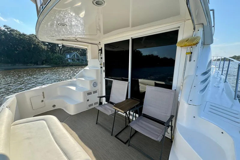 Slide: The Image of 2003 Sea Ray 400 Sedan Bridge yacht deck with chairs, table, and river view. - 19
