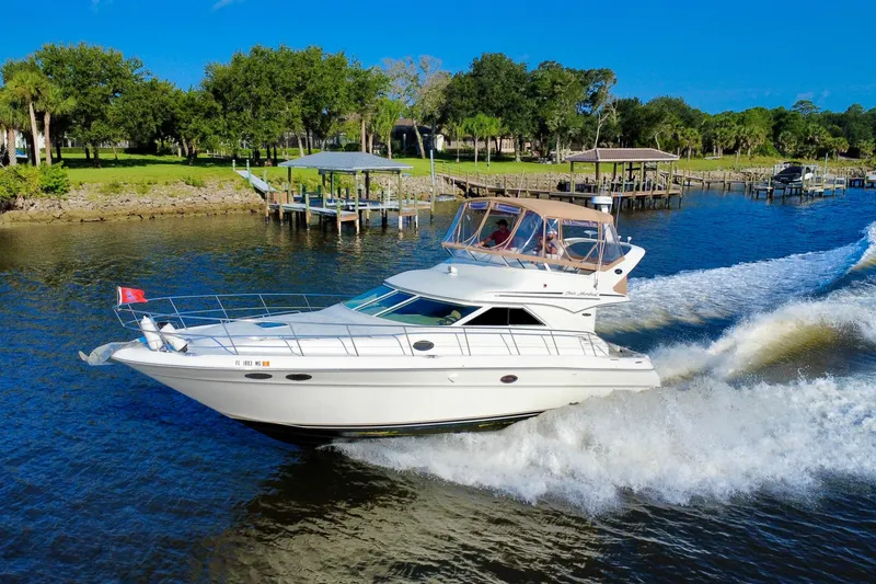 Slide: The Image of 2003 Sea Ray 400 Sedan Bridge cruising on a scenic river with lush greenery. - 3