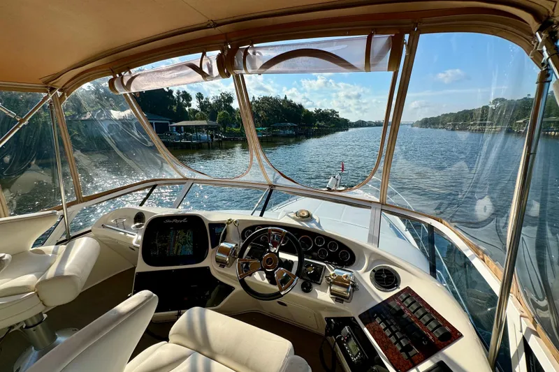 Slide: The Image of 2003 Sea Ray 400 Sedan Bridge helm with river view, featuring luxurious seating and navigation controls. - 45