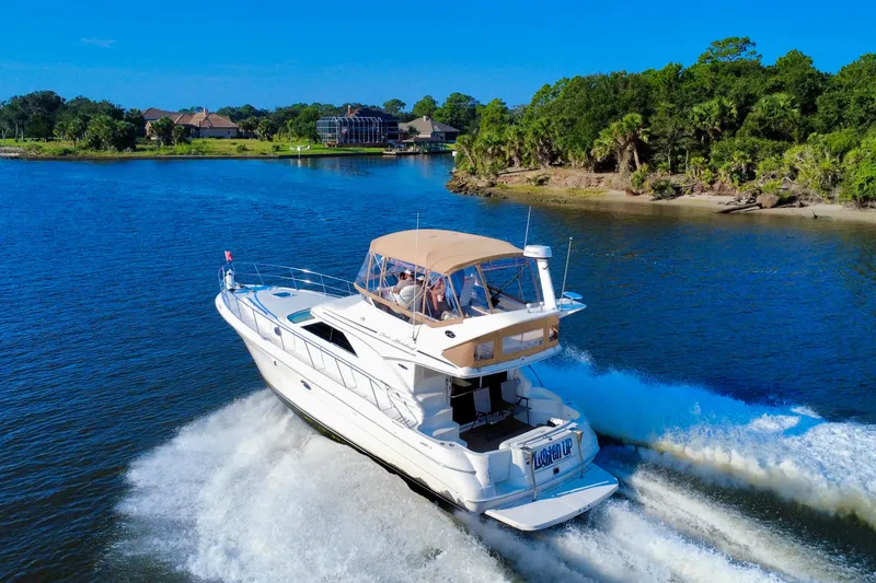Slide: The Image of 2003 Sea Ray 400 Sedan Bridge cruising on a scenic river with lush greenery. - 5