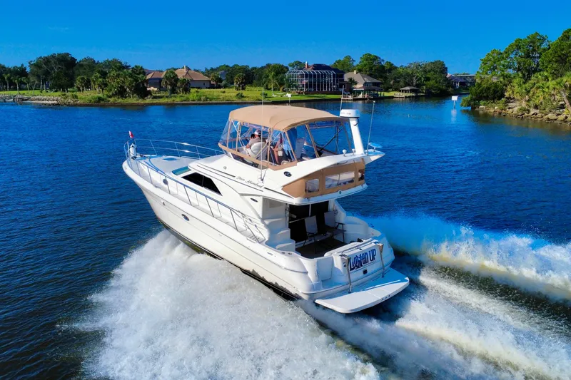 Slide: The Image of 2003 Sea Ray 400 Sedan Bridge cruising on a scenic waterway under clear blue skies. - 6