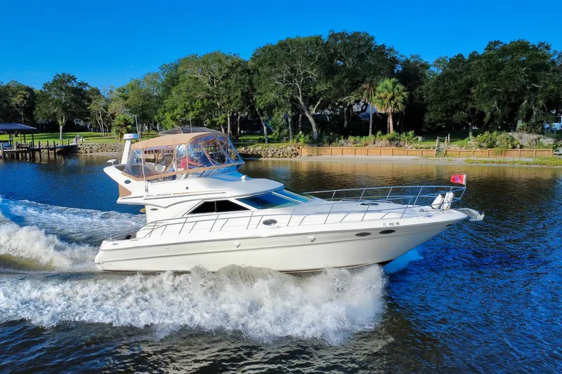 Slide: The Image of 2003 Sea Ray 400 Sedan Bridge cruising on a scenic river with lush greenery. - 9