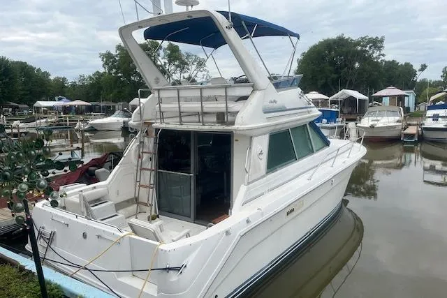 Slide: The Image of 1991 Sea Ray 370 Sedan Bridge docked at a marina, featuring a spacious deck and blue canopy. - 2