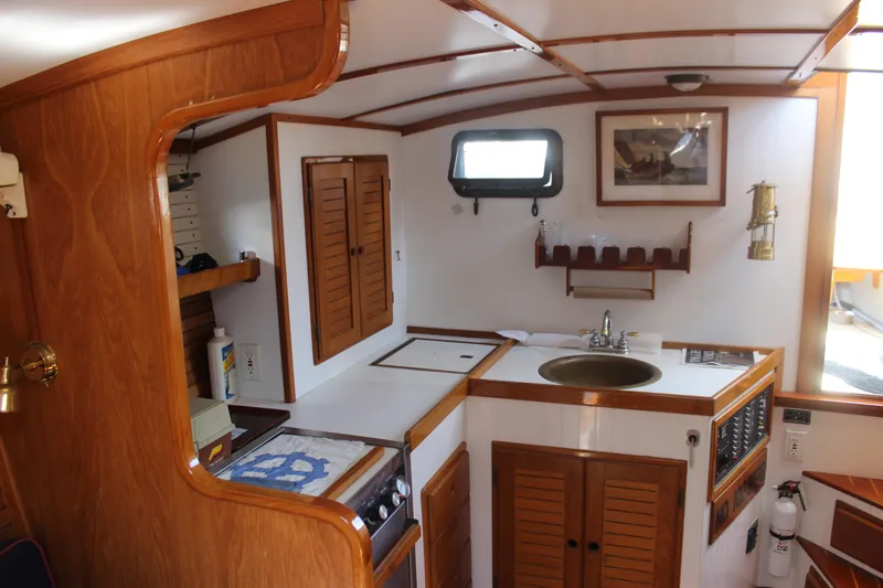 Slide: The Image of 1988 Express Yachting Scout 30 interior with wooden cabinetry and compact kitchen area. - 13