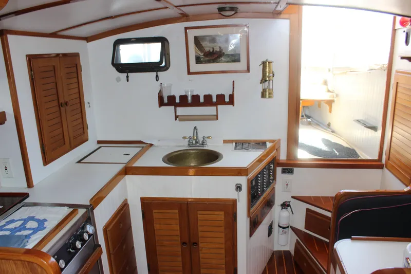 Slide: The Image of Interior of 1988 Express Yachting Scout 30, featuring a compact kitchen with wooden accents. - 14
