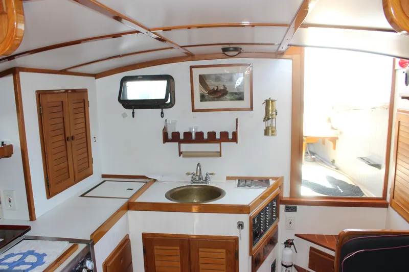 Slide: The Image of Interior of 1988 Express Yachting Scout 30, featuring a compact kitchen with wooden accents. - 15