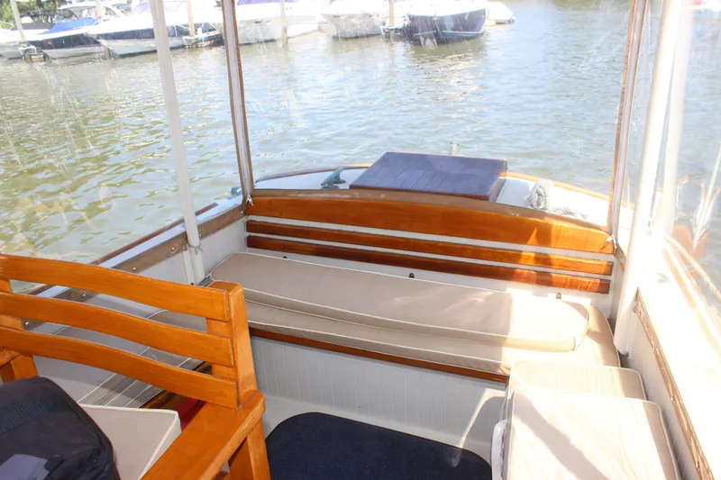 Slide: The Image of Interior view of 1988 Express Yachting Scout 30, featuring wooden seating and waterfront backdrop. - 20