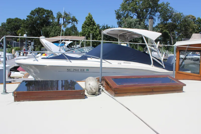 Slide: The Image of 1988 Express Yachting Scout 30 docked, featuring sleek design and canopy, surrounded by trees. - 38