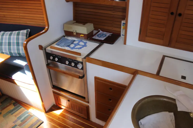 Slide: The Image of 1988 Express Yachting Scout 30 interior kitchen with stove, sink, and wooden cabinetry. - 7