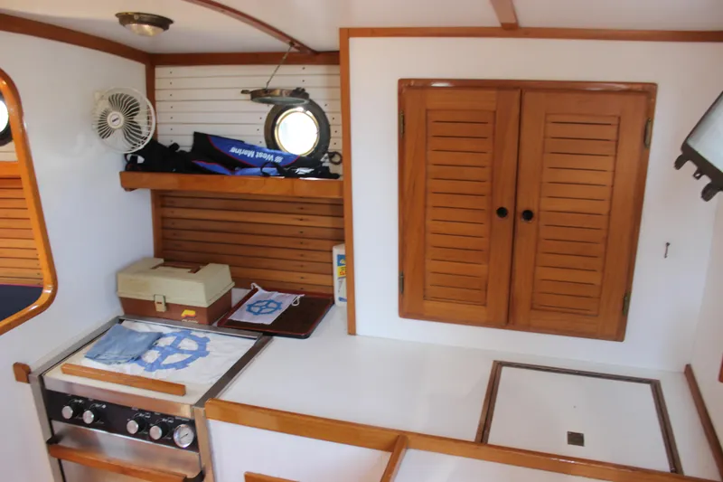 Slide: The Image of 1988 Express Yachting Scout 30 interior with wooden cabinets and compact kitchen area. - 8
