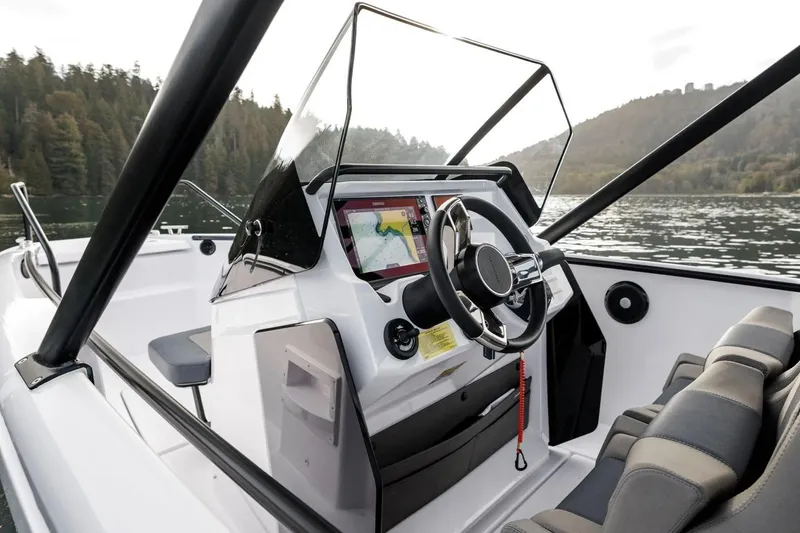 Slide: The Image of 2023 Axopar 22 T-Top boat interior with steering wheel and navigation system. - 2