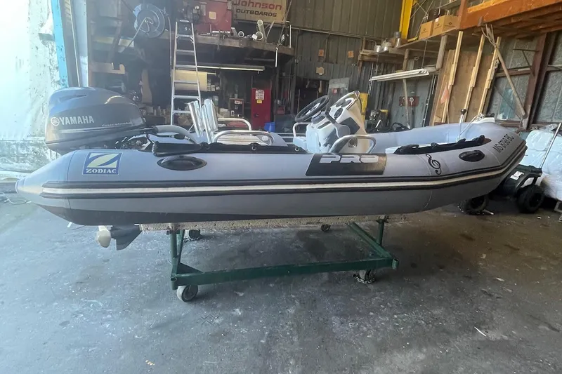 The Image of 2014 Zodiac Bayrunner 420 inflatable boat with Yamaha outboard motor in a workshop setting. - 0