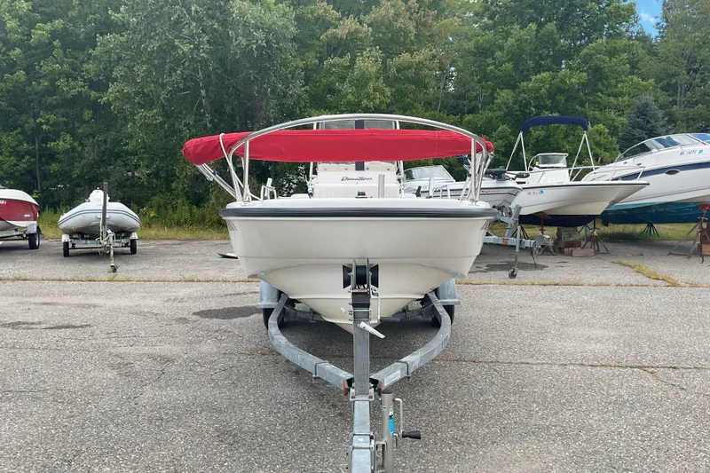 Slide: The Image of 2000 Boston Whaler Dauntless 16 boat with red canopy on trailer, surrounded by trees. - 2