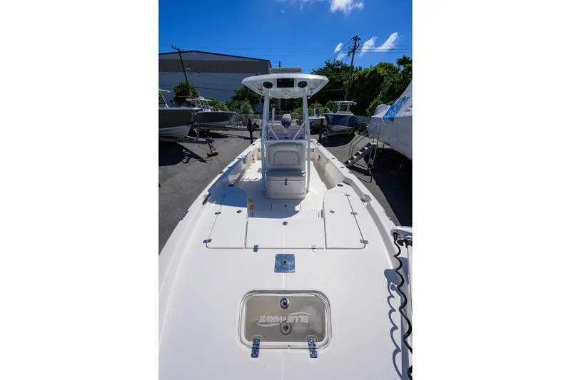 Slide: The Image of 2021 Blue Wave 2600 PureBay boat, white deck, parked outdoors under clear blue sky. - 13