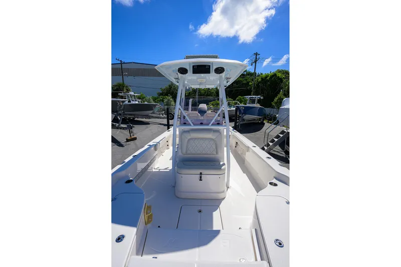 Slide: The Image of 2021 Blue Wave 2600 PureBay boat interior with seating and console under a clear blue sky. - 15