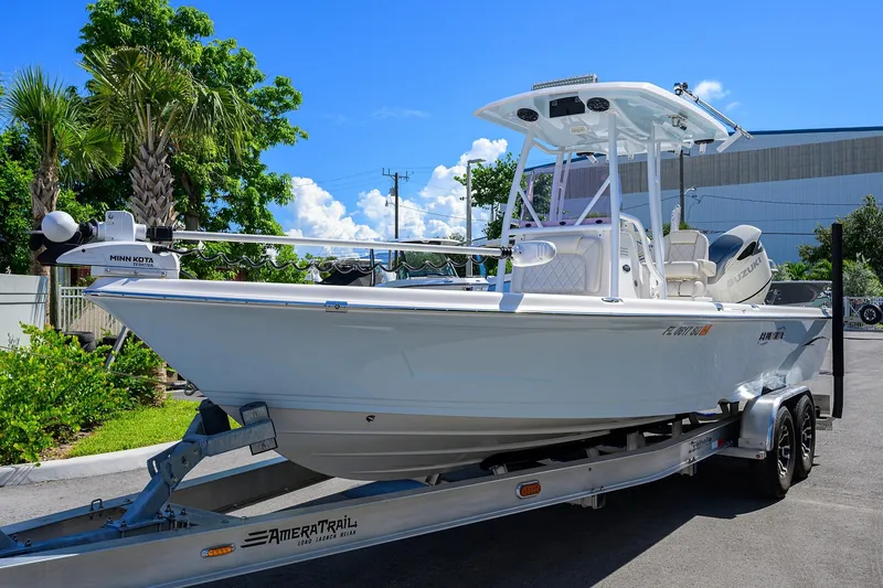 Slide: The Image of 2021 Blue Wave 2600 PureBay boat on trailer, parked outdoors under clear blue sky. - 2