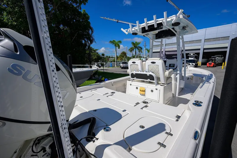 Slide: The Image of 2021 Blue Wave 2600 PureBay boat with Suzuki engine, docked outdoors under clear blue sky. - 23