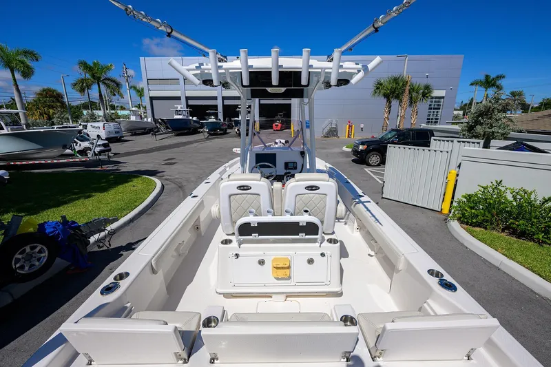 Slide: The Image of 2021 Blue Wave 2600 PureBay boat at a marina, surrounded by palm trees and parked vehicles. - 32