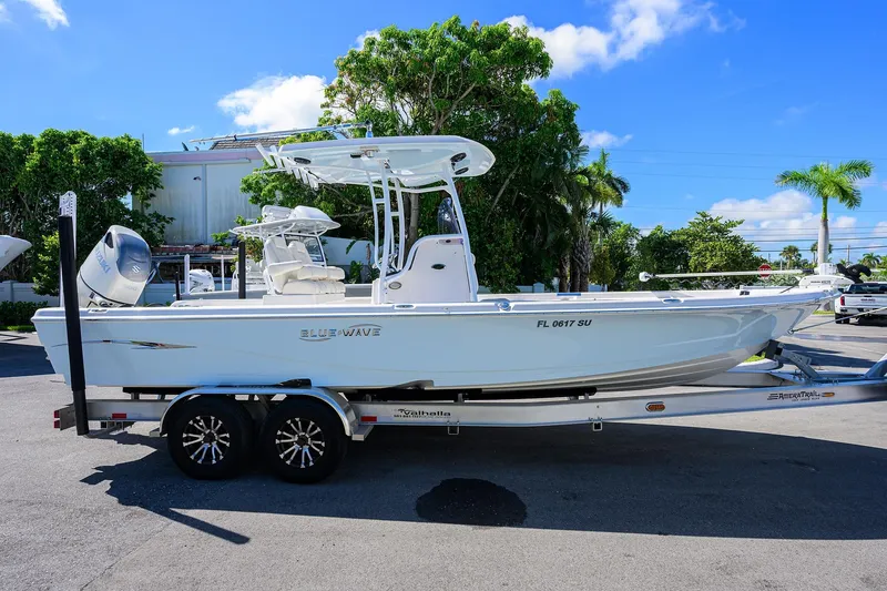 Slide: The Image of 2021 Blue Wave 2600 PureBay boat on trailer, parked outdoors under clear blue sky. - 5