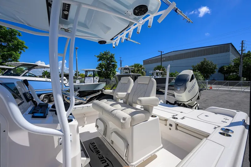 Slide: The Image of 2021 Blue Wave 2600 PureBay boat interior with seating and controls, parked outdoors. - 51