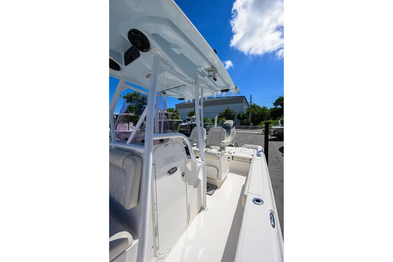Slide: The Image of 2021 Blue Wave 2600 PureBay boat interior with seating and console under clear blue sky. - 52