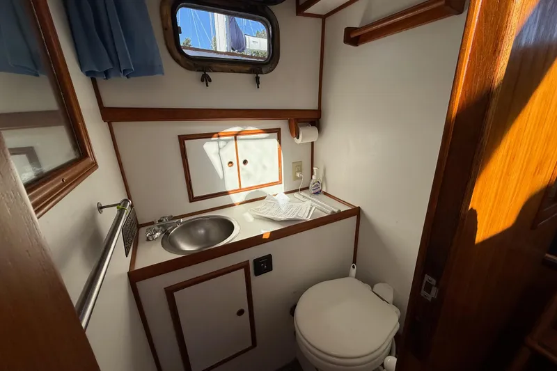 Slide: The Image of 1983 CHB 41 Classic Trawler bathroom with sink, toilet, and porthole window. - 10