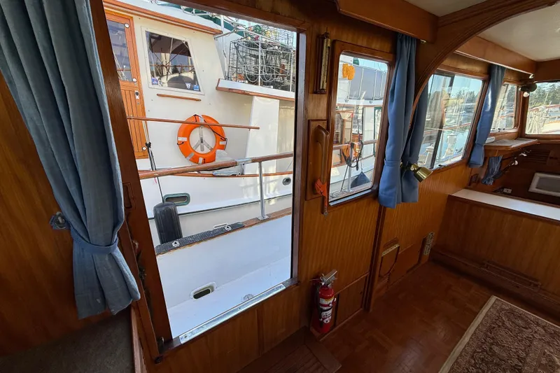 Slide: The Image of Interior view of 1983 CHB 41 Classic Trawler with wooden paneling and blue curtains. - 16