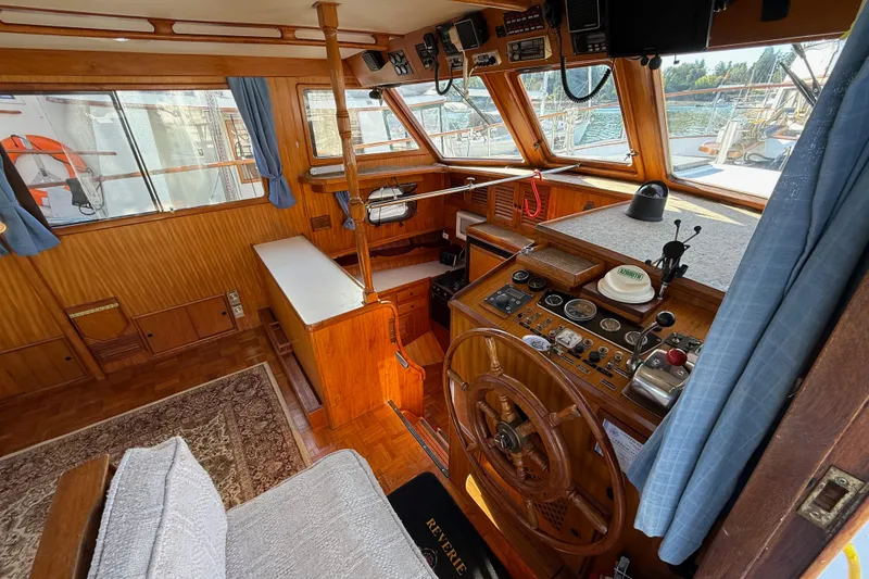 Slide: The Image of 1983 CHB 41 Classic Trawler interior with wooden helm, nautical instruments, and blue curtains. - 2