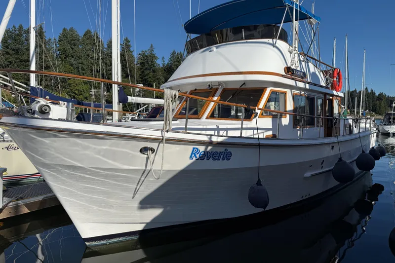 Slide: The Image of 1983 CHB 41 Classic Trawler docked, featuring white hull and blue canopy. - 21