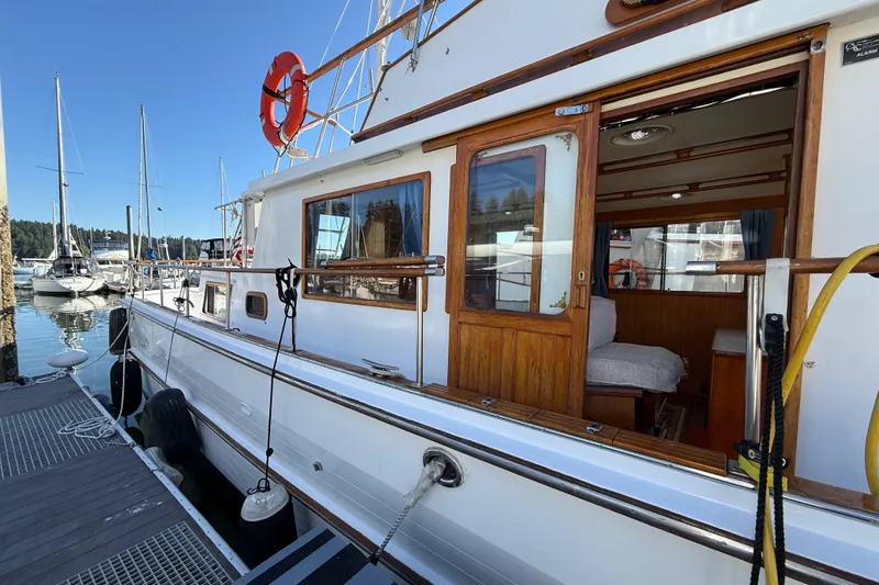 Slide: The Image of 1983 CHB 41 Classic Trawler docked, showcasing wooden details and open cabin door. - 22