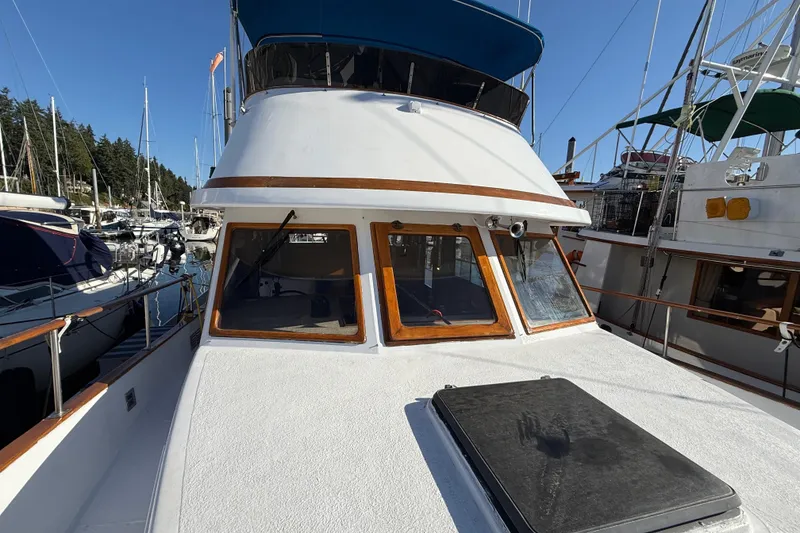 Slide: The Image of 1983 CHB 41 Classic Trawler docked at marina, showcasing front deck and cabin windows. - 26