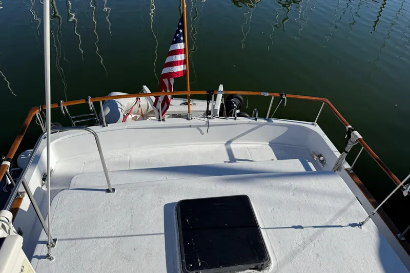Slide: The Image of 1983 CHB 41 Classic Trawler deck with American flag, docked on calm water. - 33