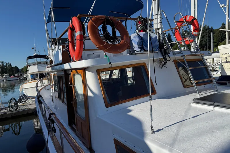 Slide: The Image of 1983 CHB 41 Classic Trawler docked, featuring life rings and blue canopy. - 35