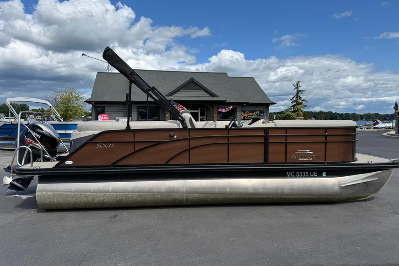 Slide: The Image of 2019 Bennington 22SX Premier pontoon boat parked on pavement under cloudy sky. - 0