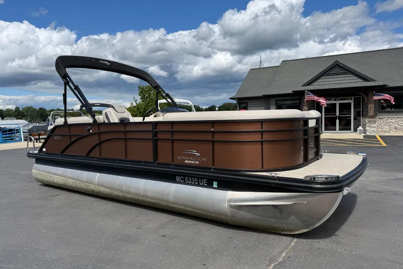 Slide: The Image of 2019 Bennington 22SX Premier pontoon boat parked outside a building under a cloudy sky. - 1