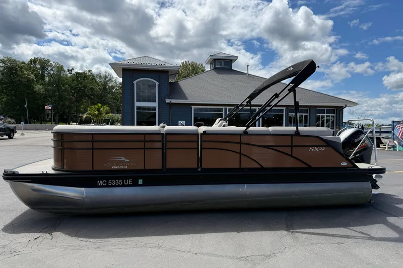 Slide: The Image of 2019 Bennington 22SX Premier pontoon boat parked near a building under a cloudy sky. - 4