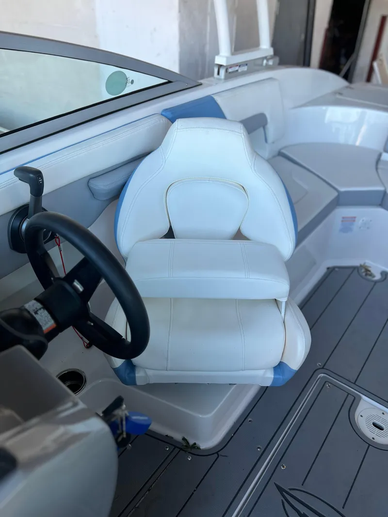 Slide: The Image of 2022 Chaparral 23 Surf boat interior with white captain's chair and steering wheel. - 15