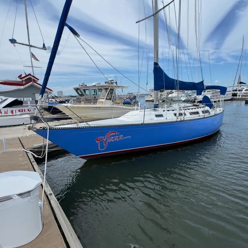 The Image of 1986 Catalina 38 sailboat docked at marina, blue hull, clear sky background. - 0