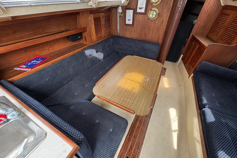 Slide: The Image of 1986 Catalina 38 sailboat interior with wooden table, blue cushioned seating, and nautical decor. - 24