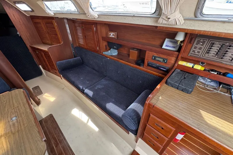 Slide: The Image of Interior of 1986 Catalina 38 sailboat with wooden cabinetry and blue upholstered seating. - 25