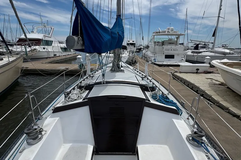 Slide: The Image of 1986 Catalina 38 sailboat docked at marina, surrounded by other boats under a blue sky. - 6