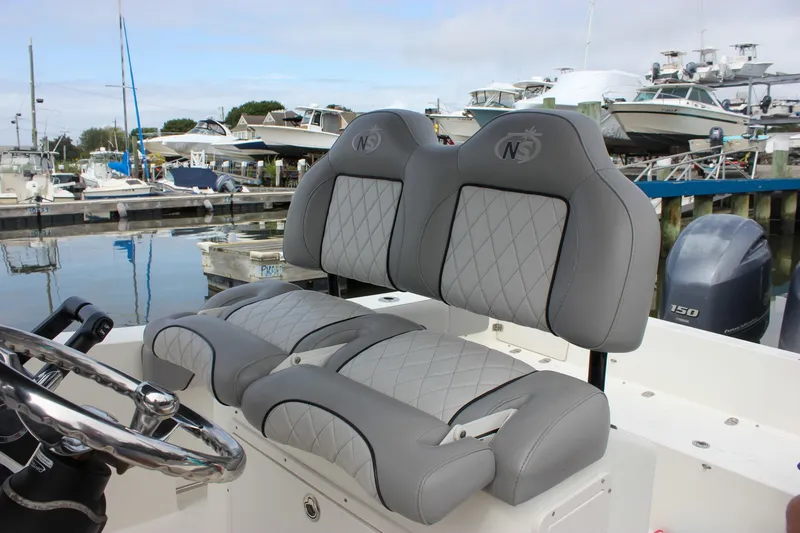 Slide: The Image of 2017 NauticStar 2602 Legacy boat seats with quilted gray upholstery at a marina. - 35